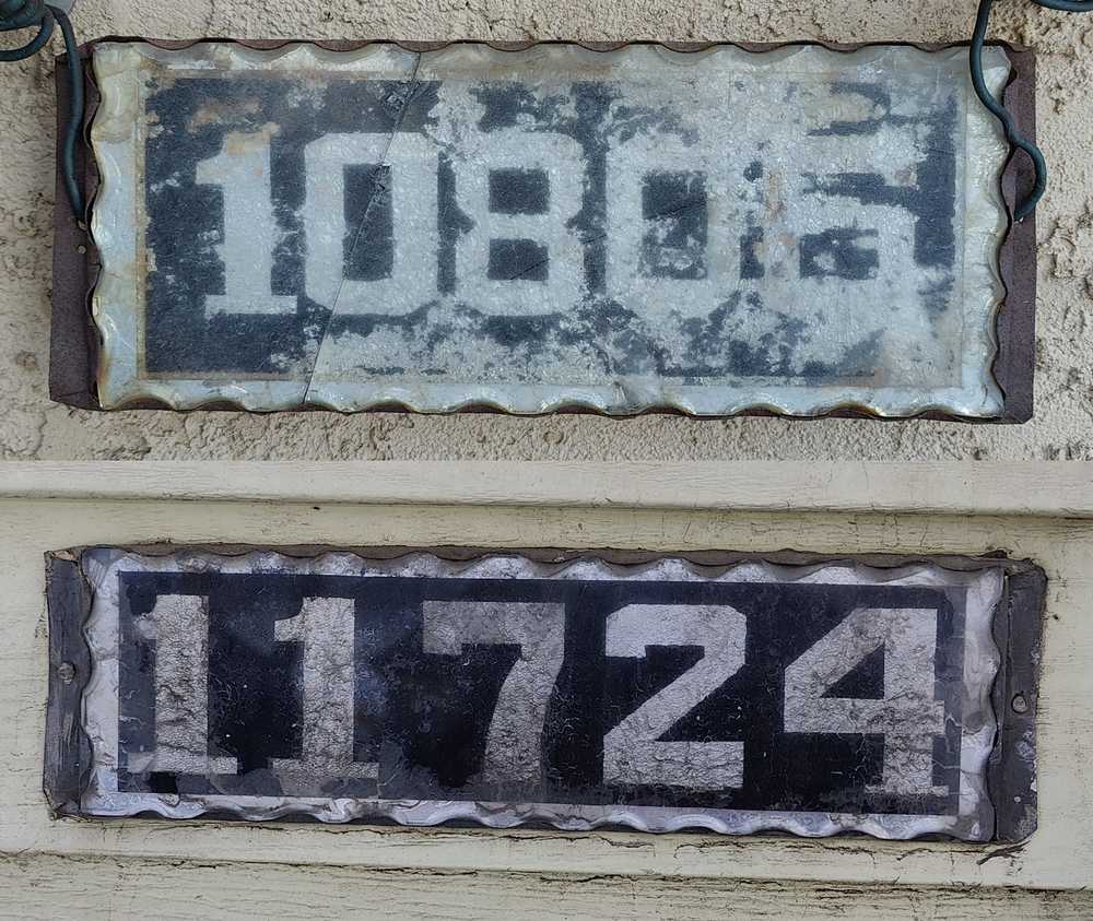 Two old house number plates sharing similar characteristics.