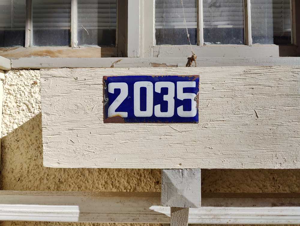 A rusty blue enamel plaque screwed onto an old wall.