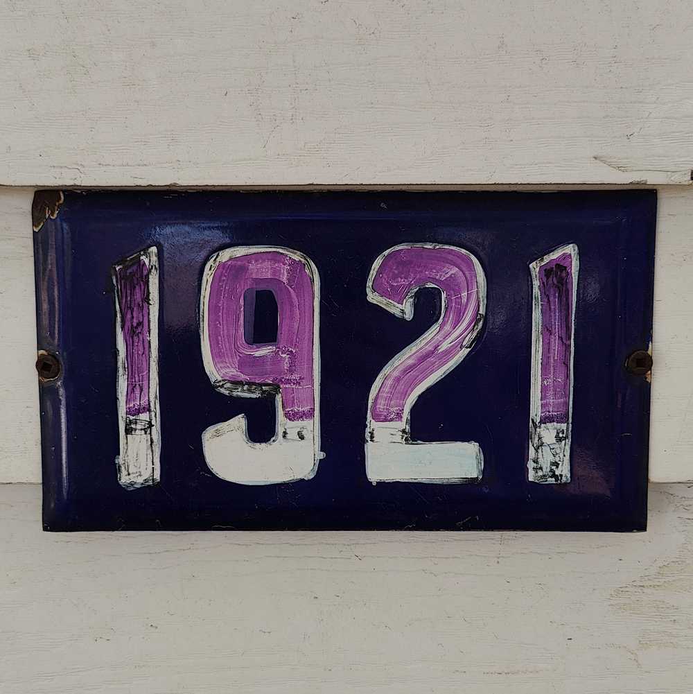 A number plate decorated with purple marker.