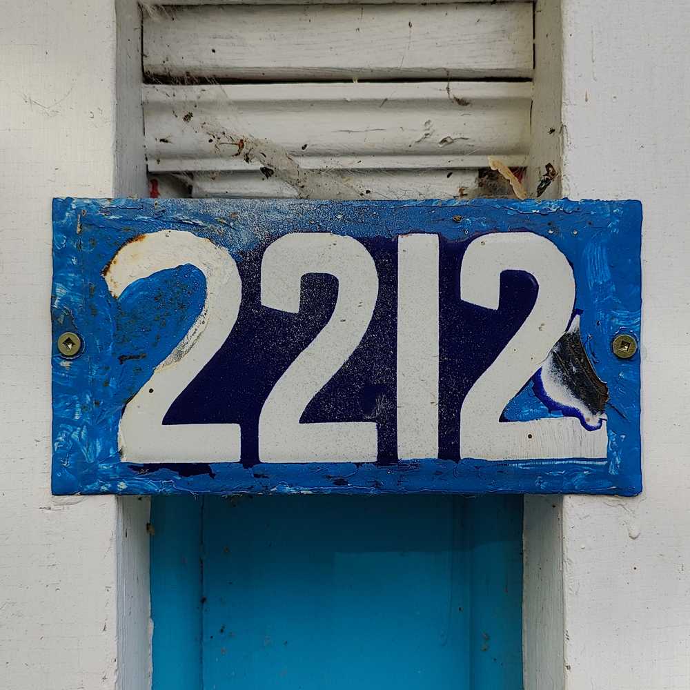 A damaged number plate covered with azure paint all around the edges.