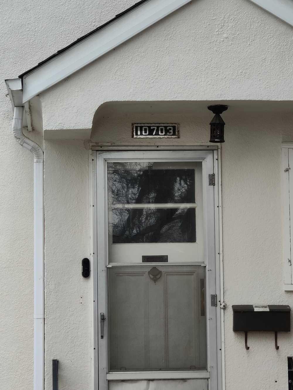 An old glass-and-foil house number plate installed above a door.