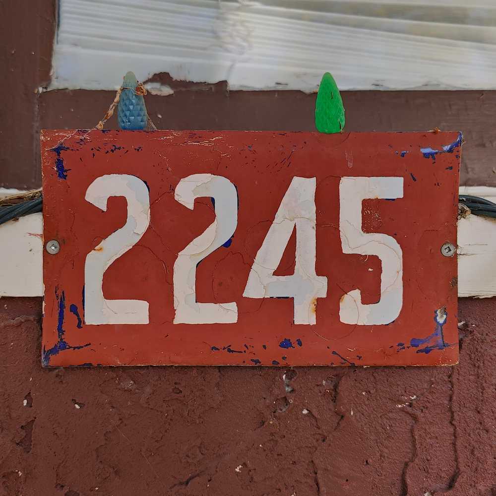 A number plate painted red to match its stucco.